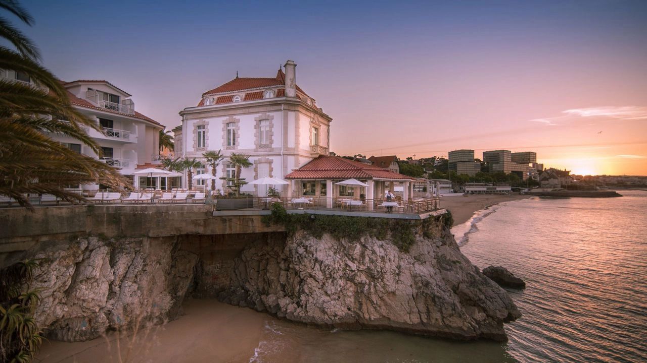 Royal and elegant looking cliffside hotel with the ocean and sunset in the background