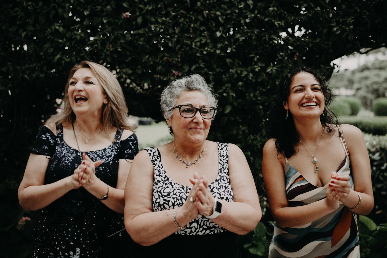 Three ladies clapping, celebrating, and smiling as guests in a Portuguese destination wedding