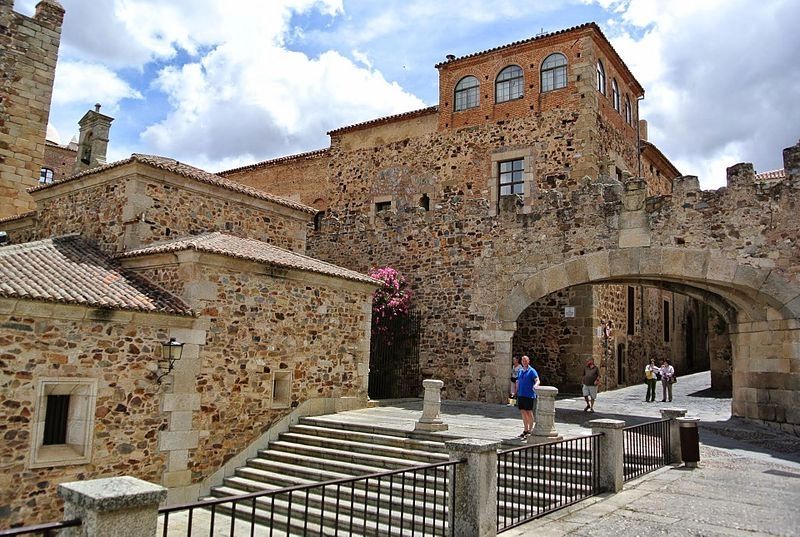 A medieval building in Càceres, Spain with people walking and visiting