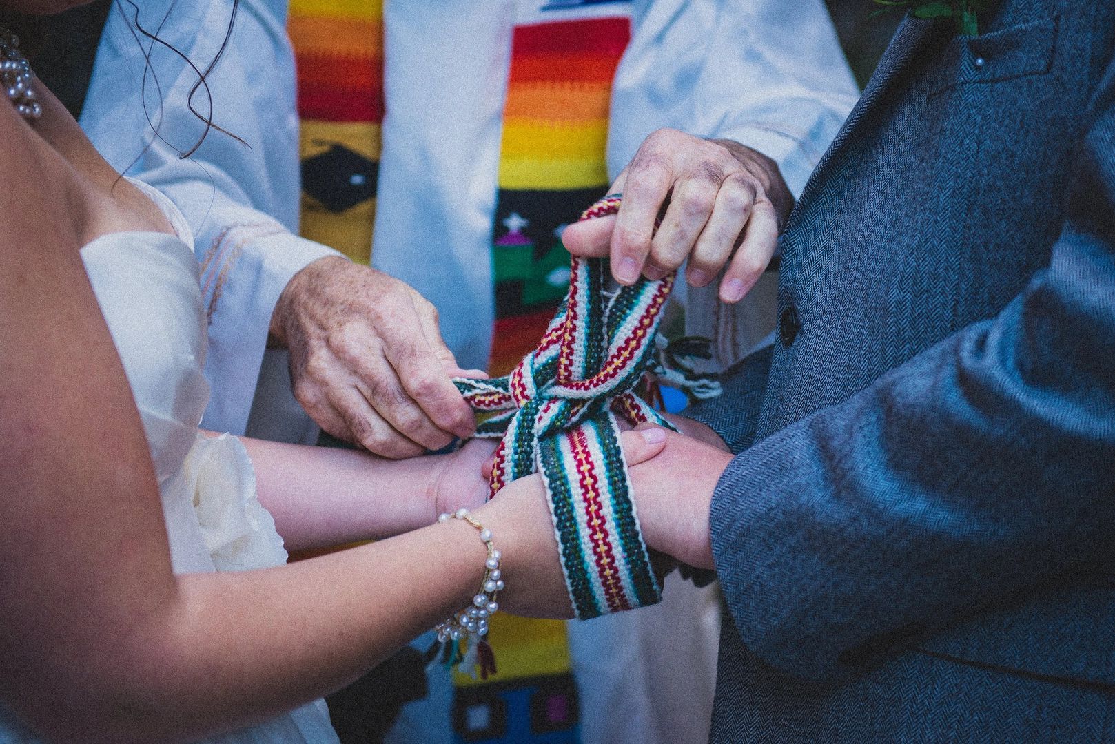 Hands of the bride, groom, and their celebrant showing a Celtic handfasting ceremony for a destination wedding in Ireland