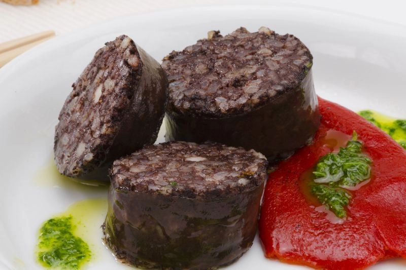 Traditional black pudding dish with red sauce on a white plate
