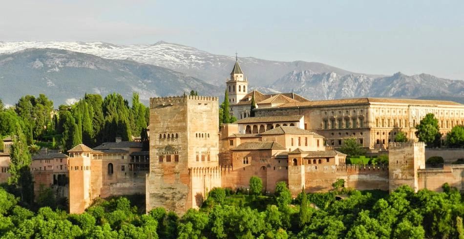 A large historic castle in Andalusia with a beautiful mountain range behind it