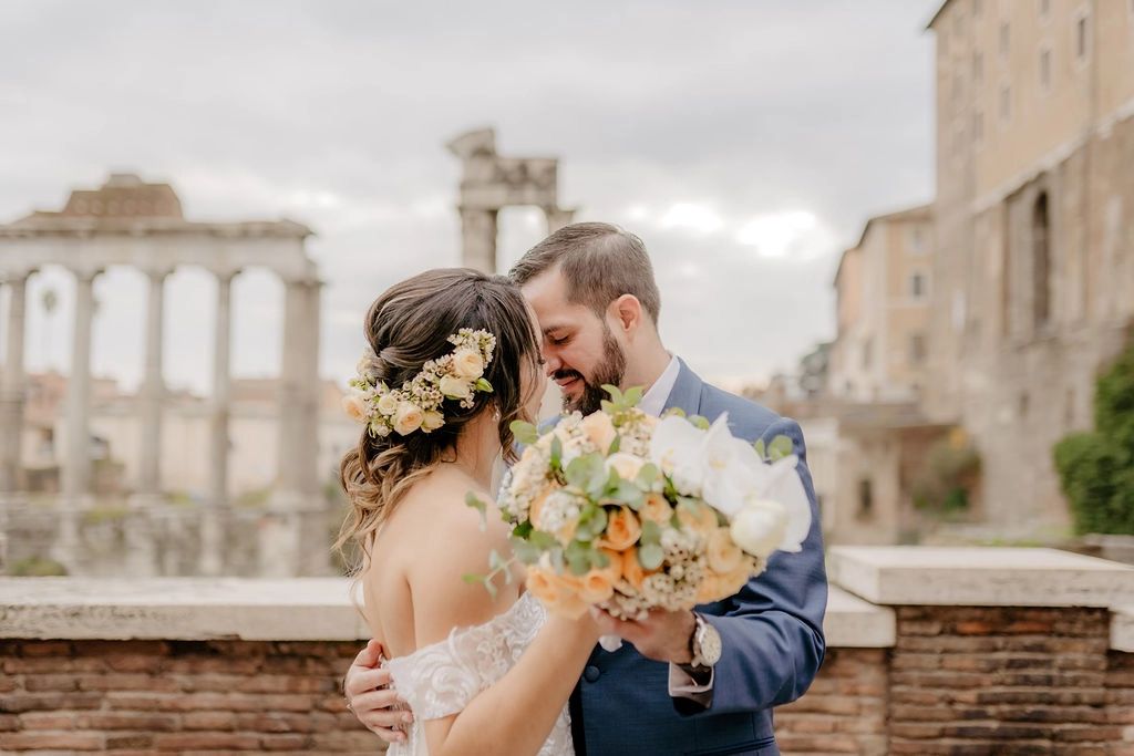 Bride and groom havign a romantic photoshoot with the Colosseum and Roman Forum in the background during their elopement in Italy