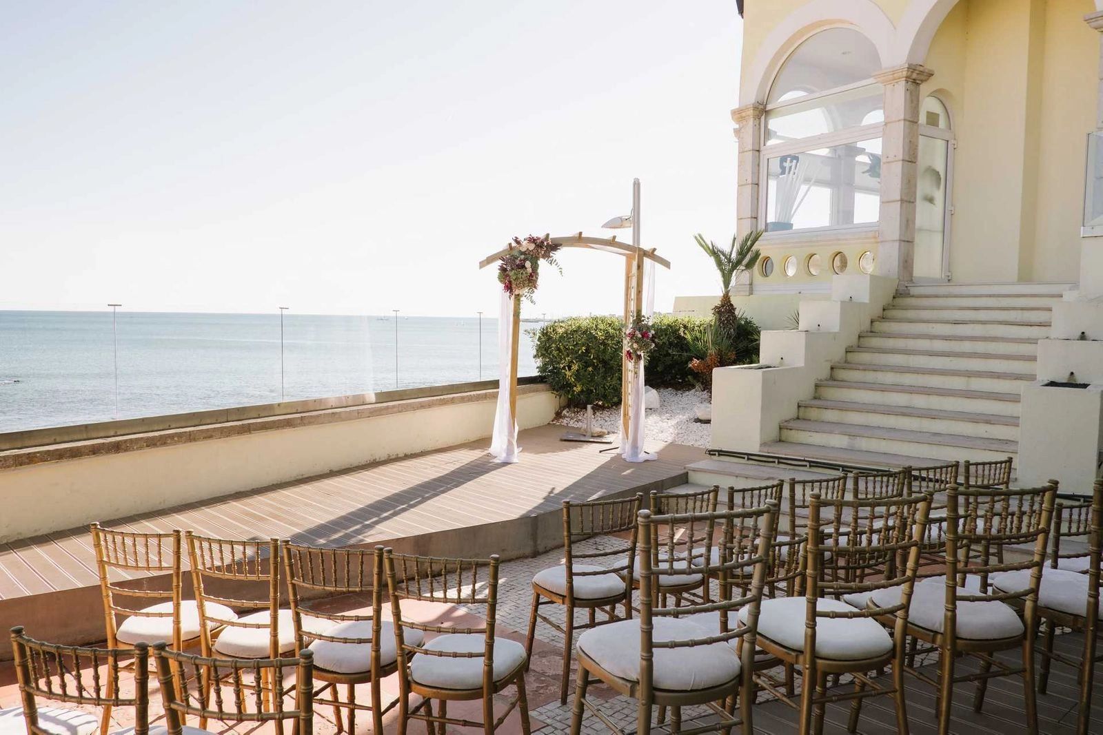 A seaside palace hotel in Lagos, Portugal with chairs and an arch arranged for a wedding ceremony