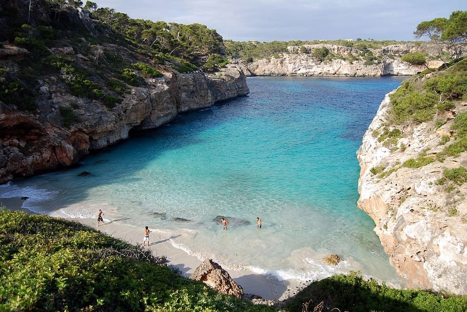 Mallorca’s turquoise waters and pristine beaches with white and gray cliff rocks, and a few people walking