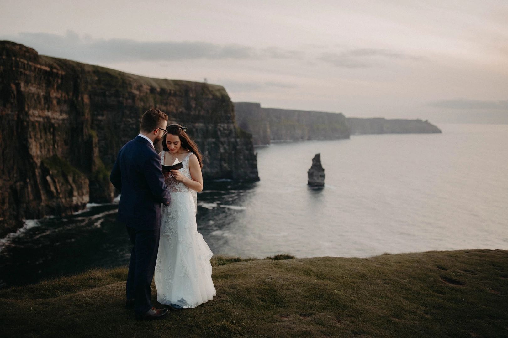 Bride reading her vows to her groom with the Cliffs of Moher in the background during their Irish destination wedding