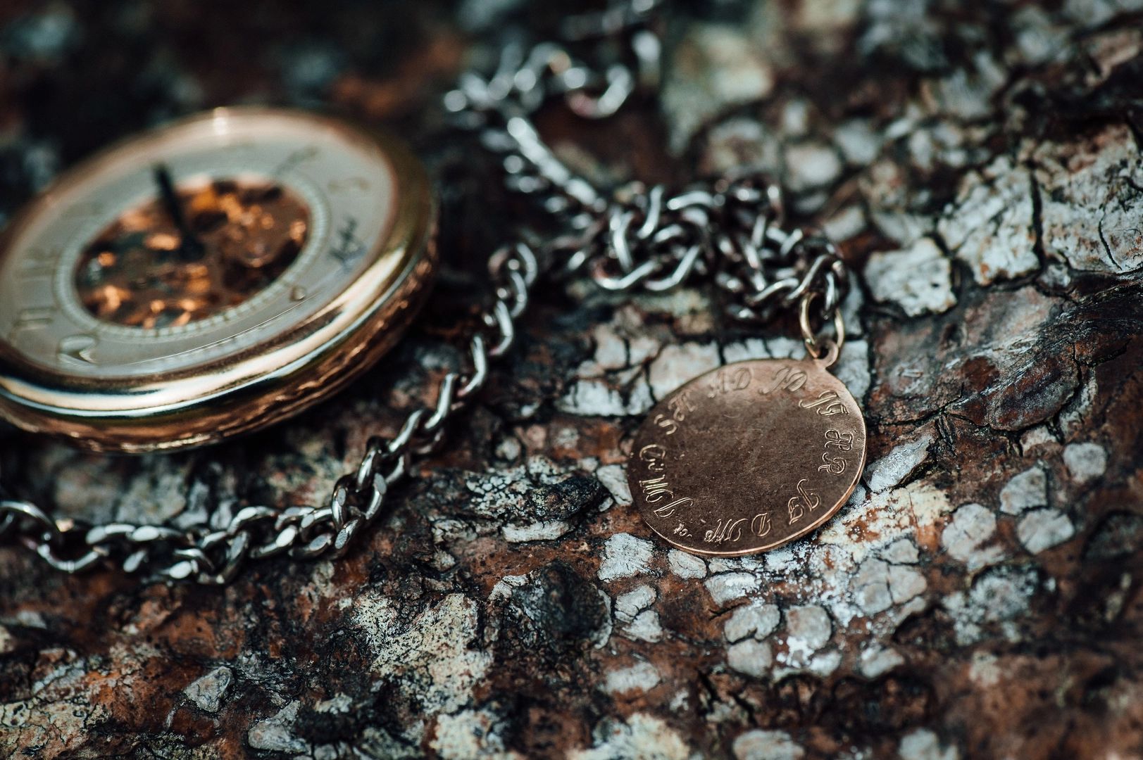 A bronze coin attached to a silver chain on top of a cemented surface
