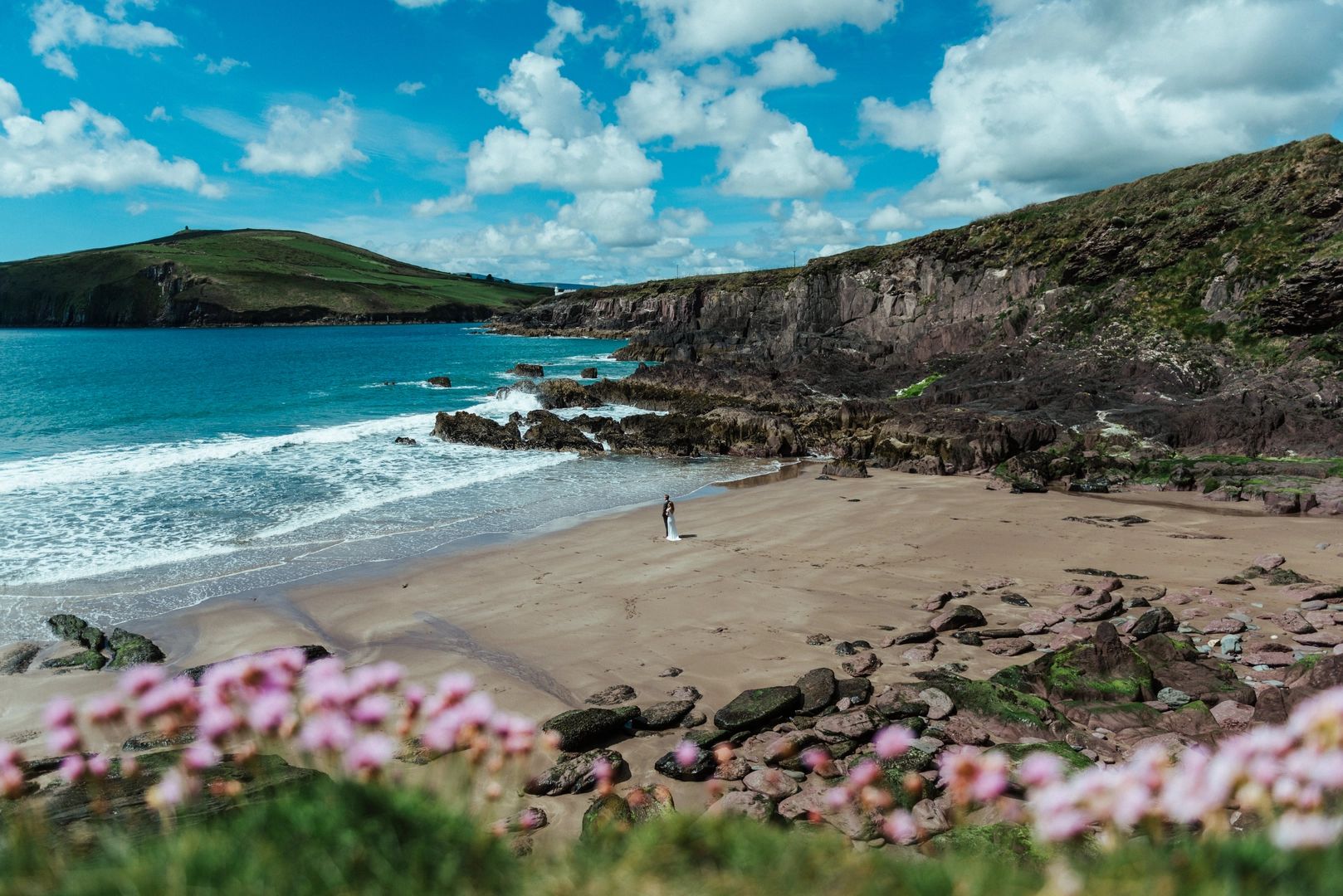 A wide shot of the Kilmurry Beach with cliffs, the wild Atlantic coastline, and a couple