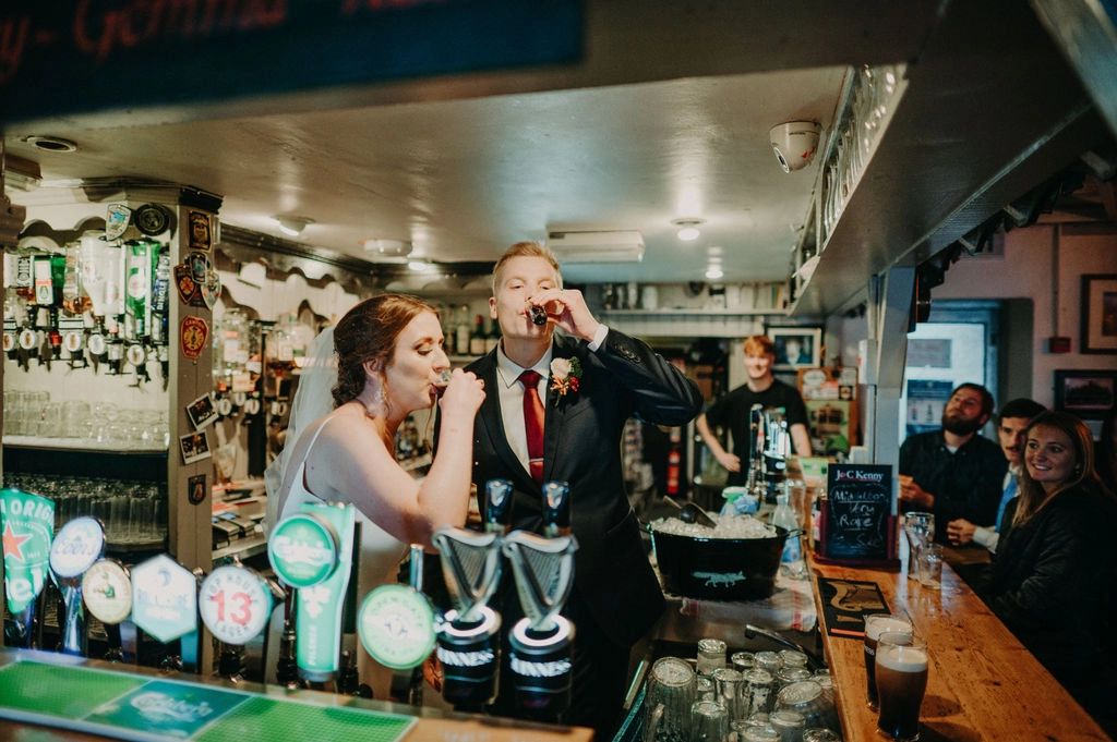 Bride and groom drink shots of liquor inside a traditional Irish pub during their elopement in Ireland