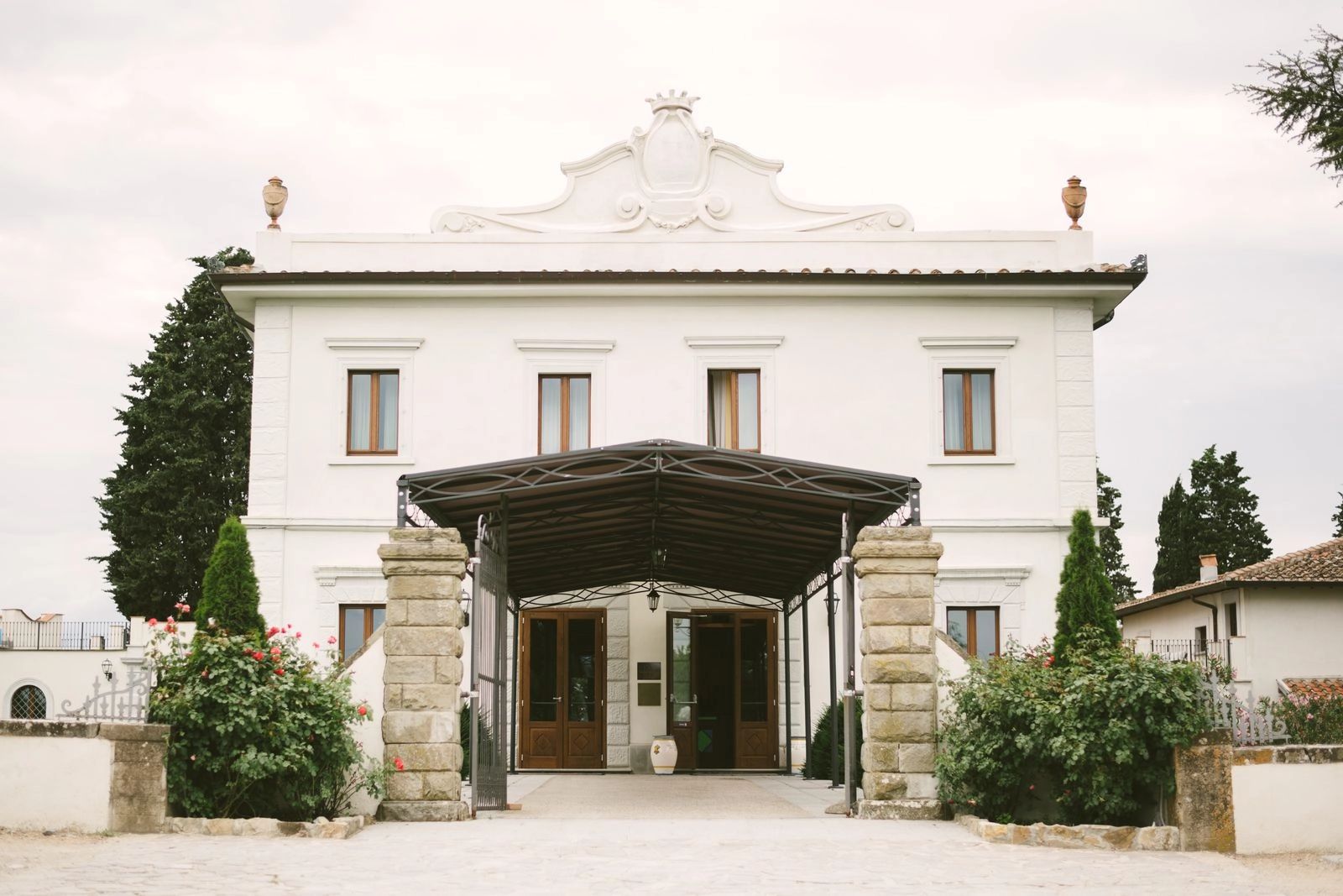 An elegant, white Italian villa surrounded by trees 