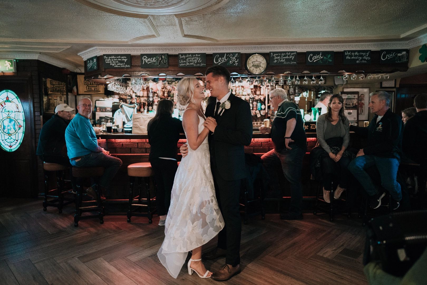 Newlyweds dancing and laughing inside an Irish pub to celebrate their destination elopement in Ireland