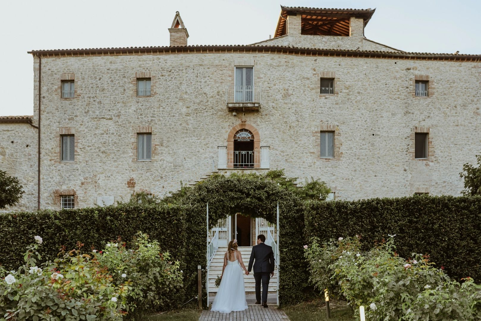 Bride and groom posing in front of a castle wedding venue in Italy