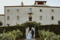 Bride and groom posing in front of a castle wedding venue in Italy