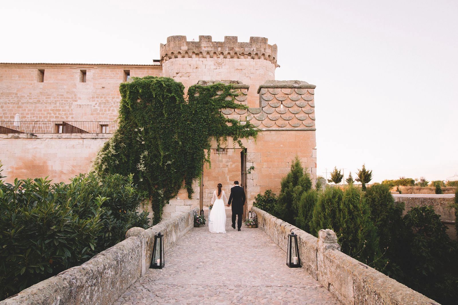 Bride and groom walking towards the entrance of a historic building in Spain
