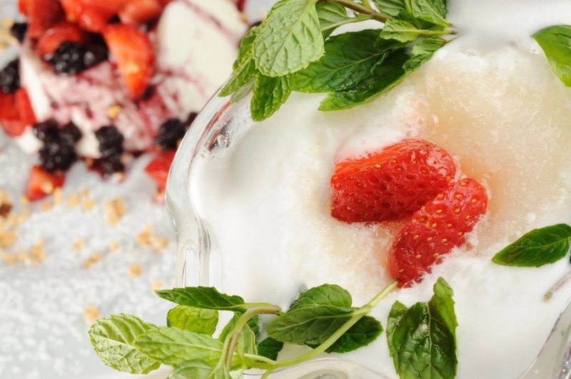 Close-up shot of a sorbet with strawberry slices and green leaves on top
