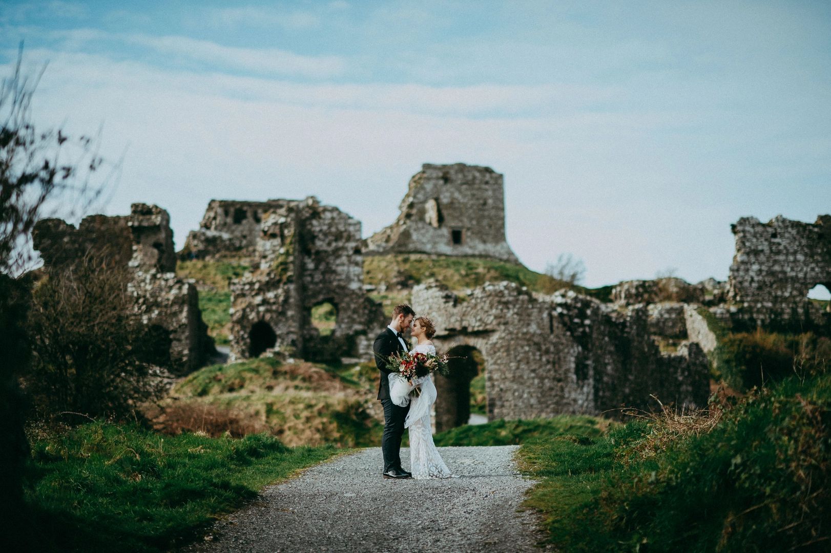 Bride and groom hugging each other with building ruins in the background during their destination wedding in Ireland