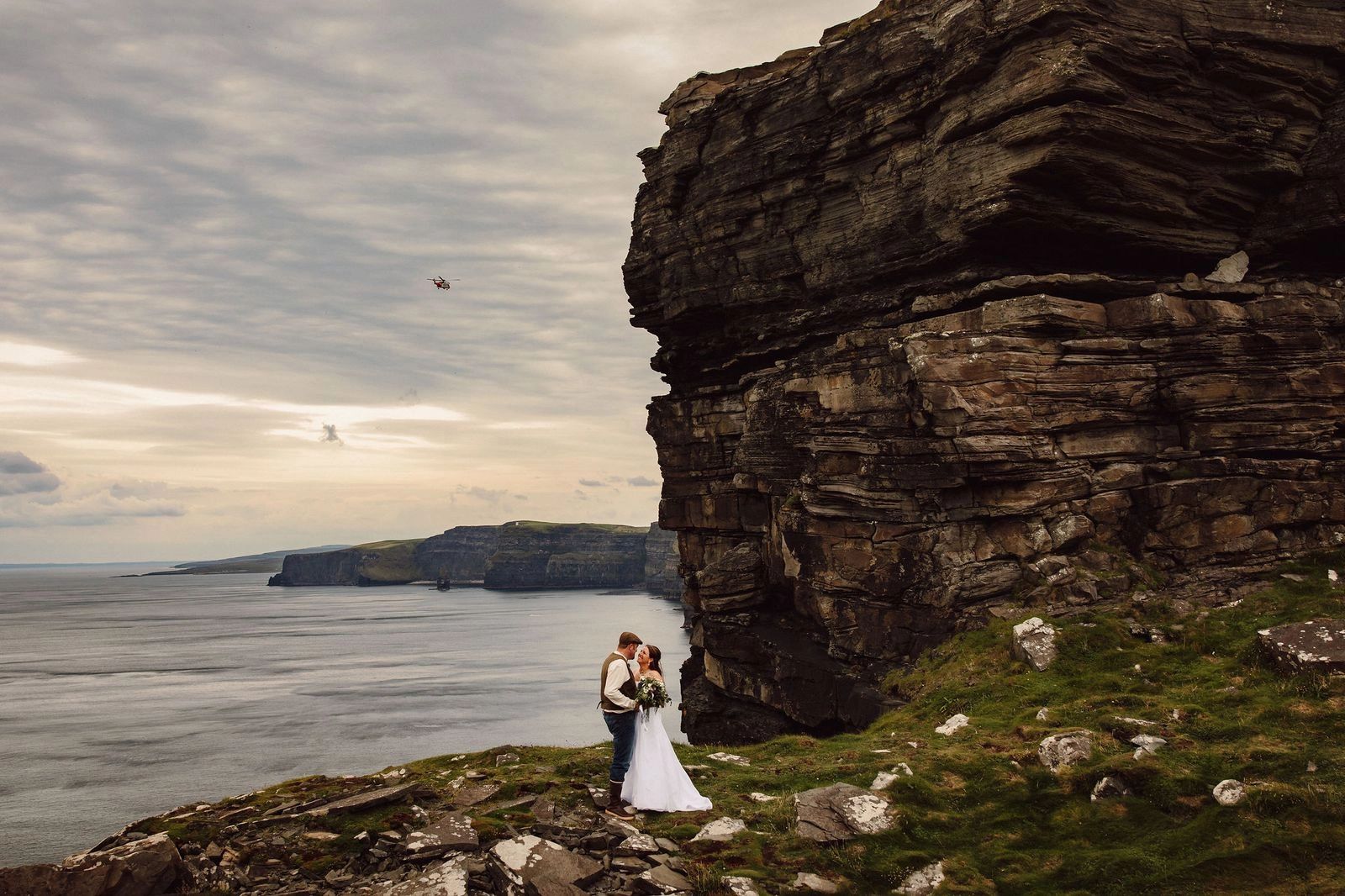 Bride and groom looking at each other during the photoshoot of their destination wedding in Ireland atop the cliffs in Clare