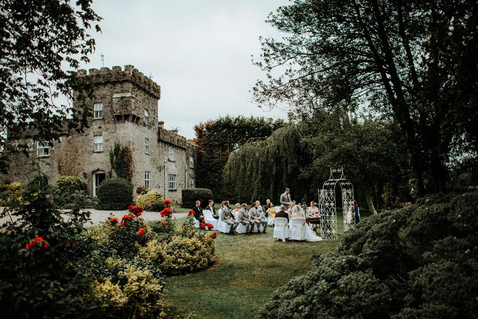 A garden ceremony for a destination wedding in Ireland with a historic castle in the background