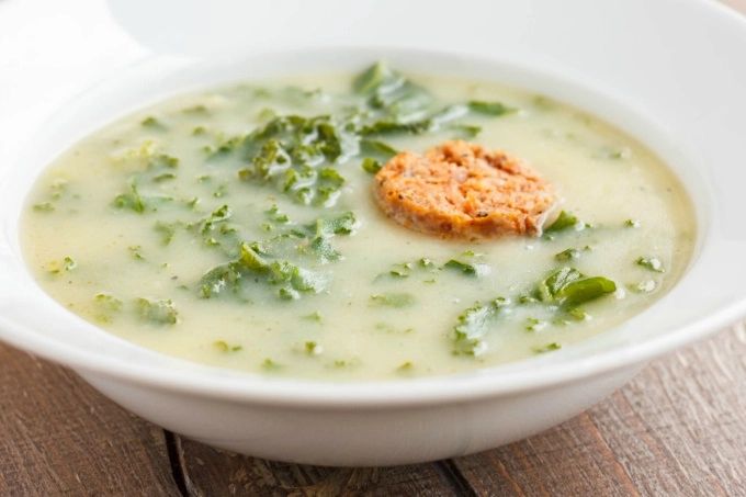 A close-up shot of a caldo verde soup in a white bowl