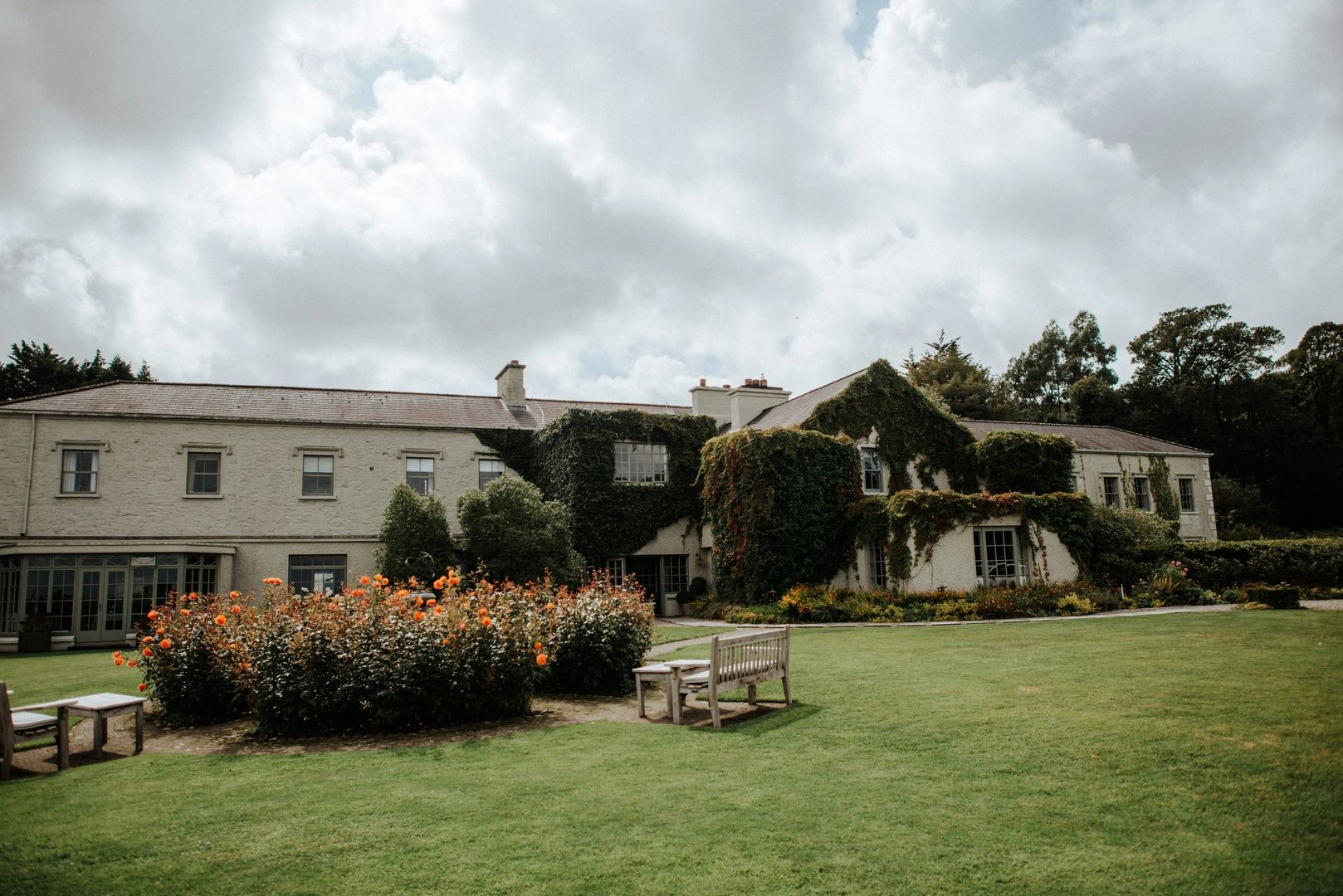 A hotel that looks like a country house partially with a facade covered in greenery
