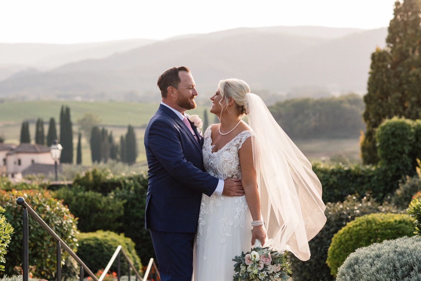 Newlyweds having a photoshoot after their destination wedding in Italy, with the Tuscan countryside in the background