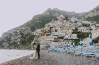 Bride and groom standing along the Amalfi coast with buildings behind them at an elopement in Italy