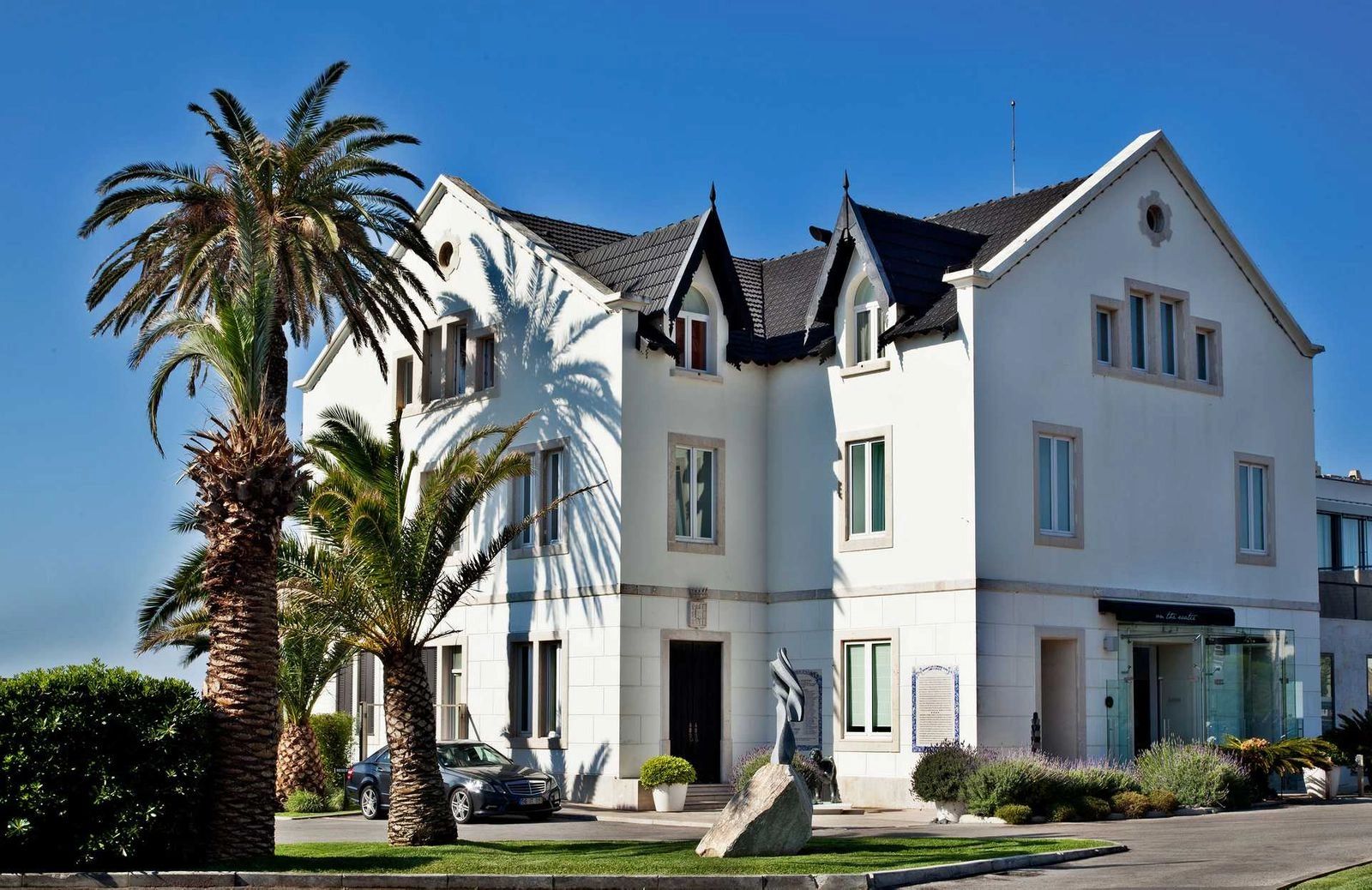 Small white hotel with tropical trees outside for destination weddings in Portugal