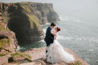 Groom hugging bride on top of a cliff at an elopement in Ireland.