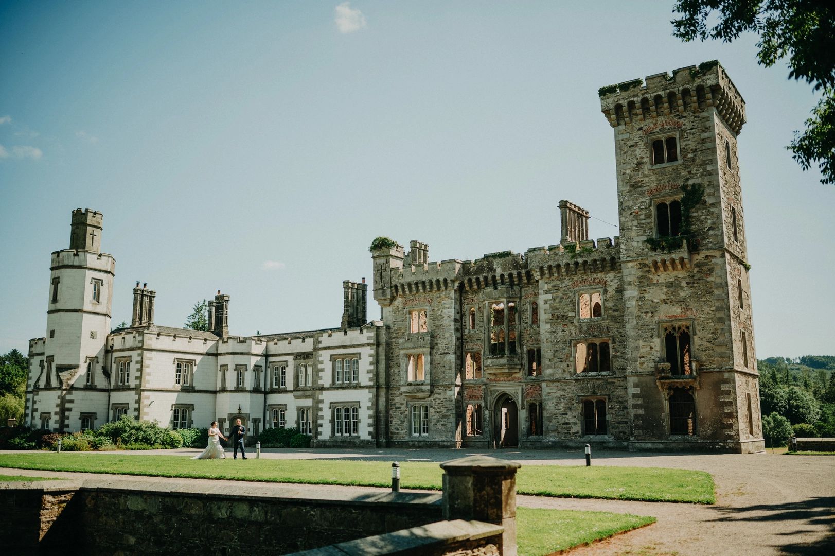 Newlyweds walking in front of a castle on a sunny day in Ireland