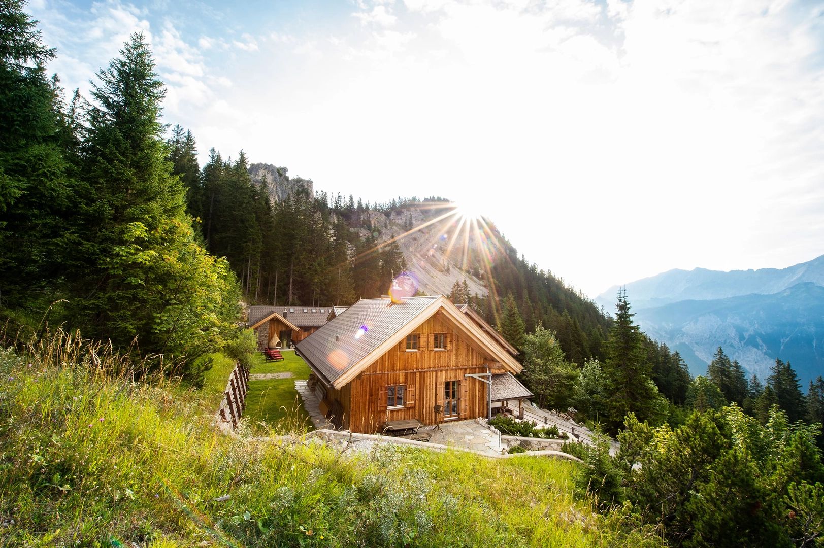 Wooden lodge surrounded by forests with mountains in the background in Austria