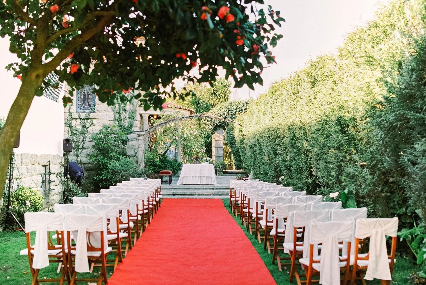 Chairs and a red carpet are arranged for an outdoor ceremony framed by lush greens in a Portugal venue