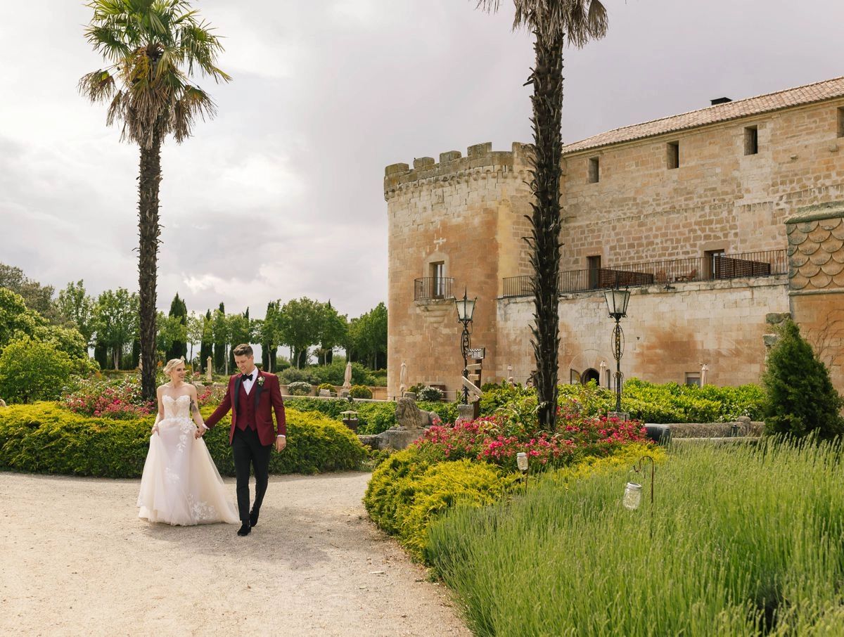 Bride and groom walking with a castle backdrop for their destination wedding in Spain