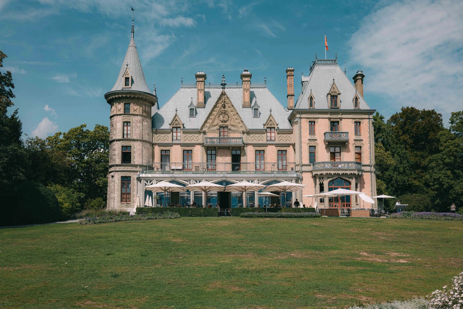 Peach-colored castle with amidst lush greenery in Switzerland