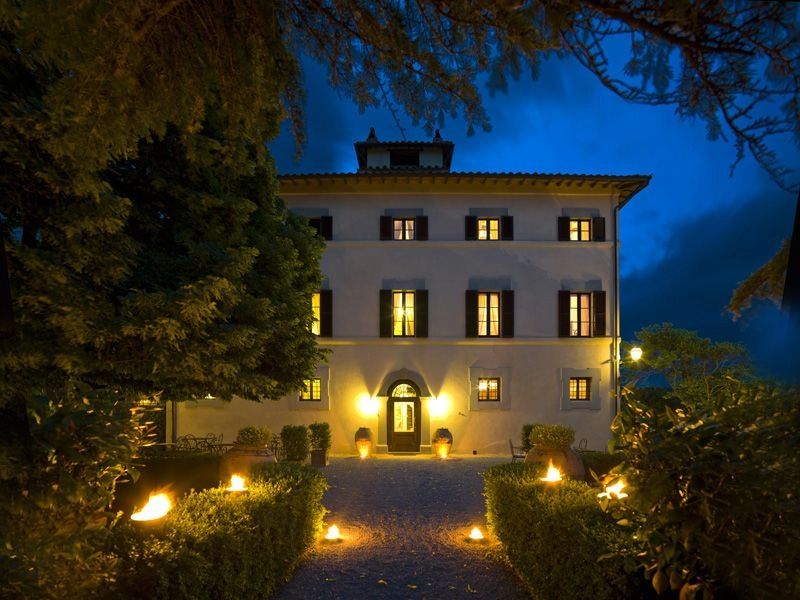 Well-lit villa under the night sky surrounded by trees in Italy