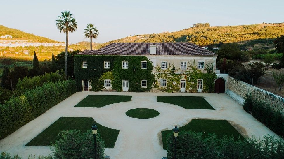 Palace half-covered in ivy plants with formal garden in front in Portugal