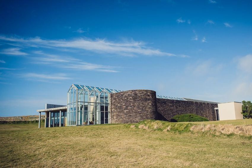 Historic museum with a glass-walled indoor area amidst a wide green field