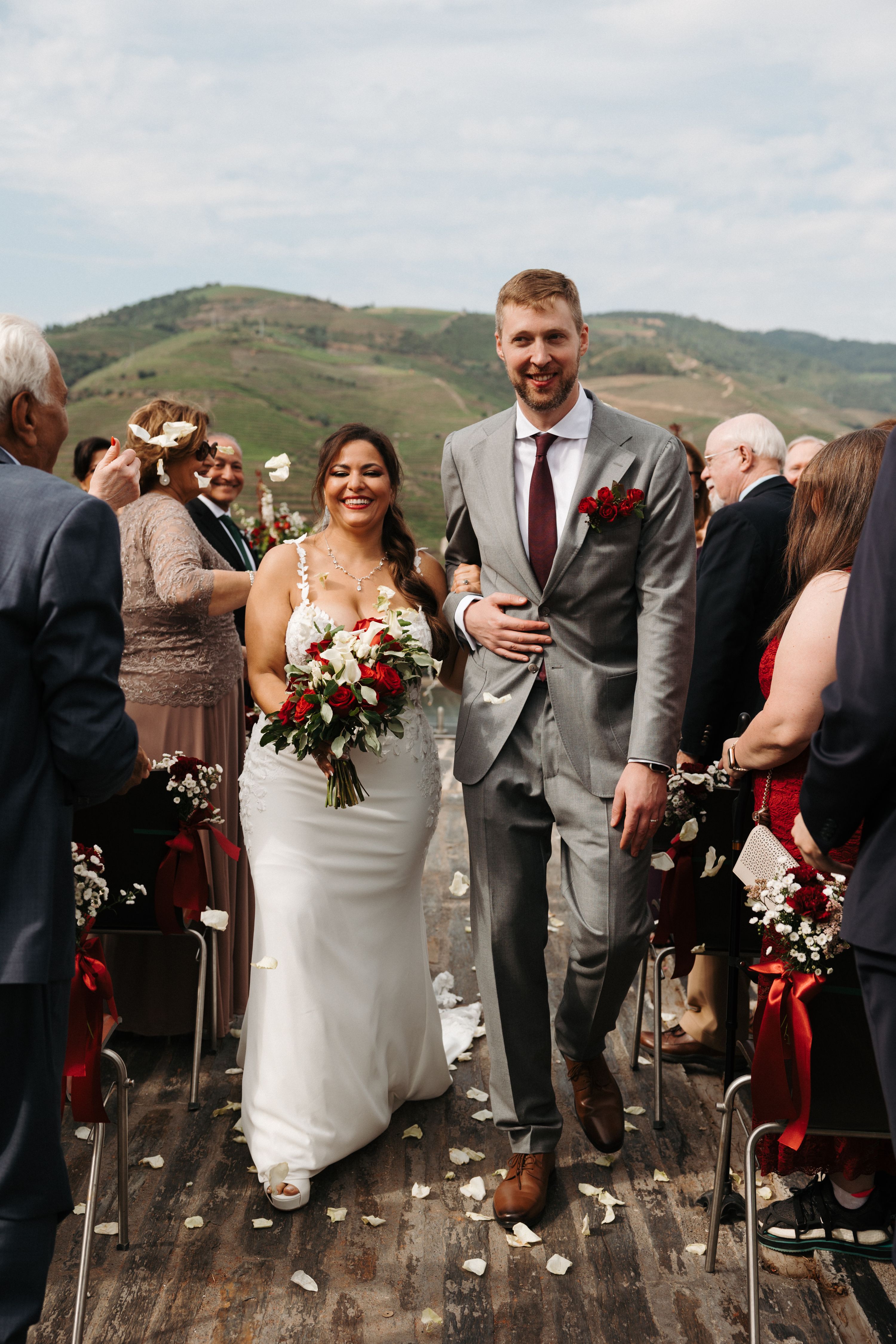 Newlyweds walking down the aisle with a mountain panorama behind them during their destination wedding in Portugal