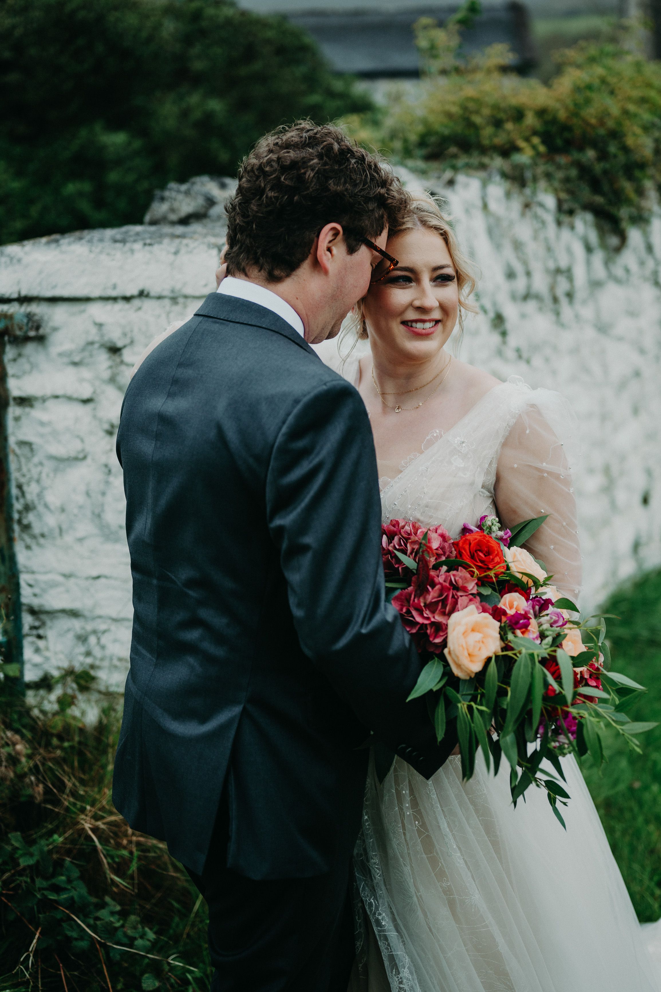 Bride and groom share a quiet moment with vibrant bouquet at a small wedding in Ireland