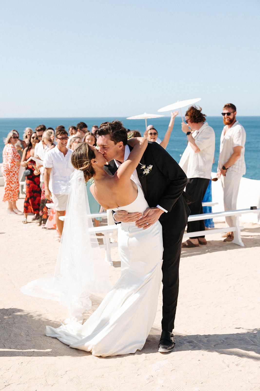 Newlyweds kissing on the cliffs of Algarve during the ceremony of their elopement in Portugal