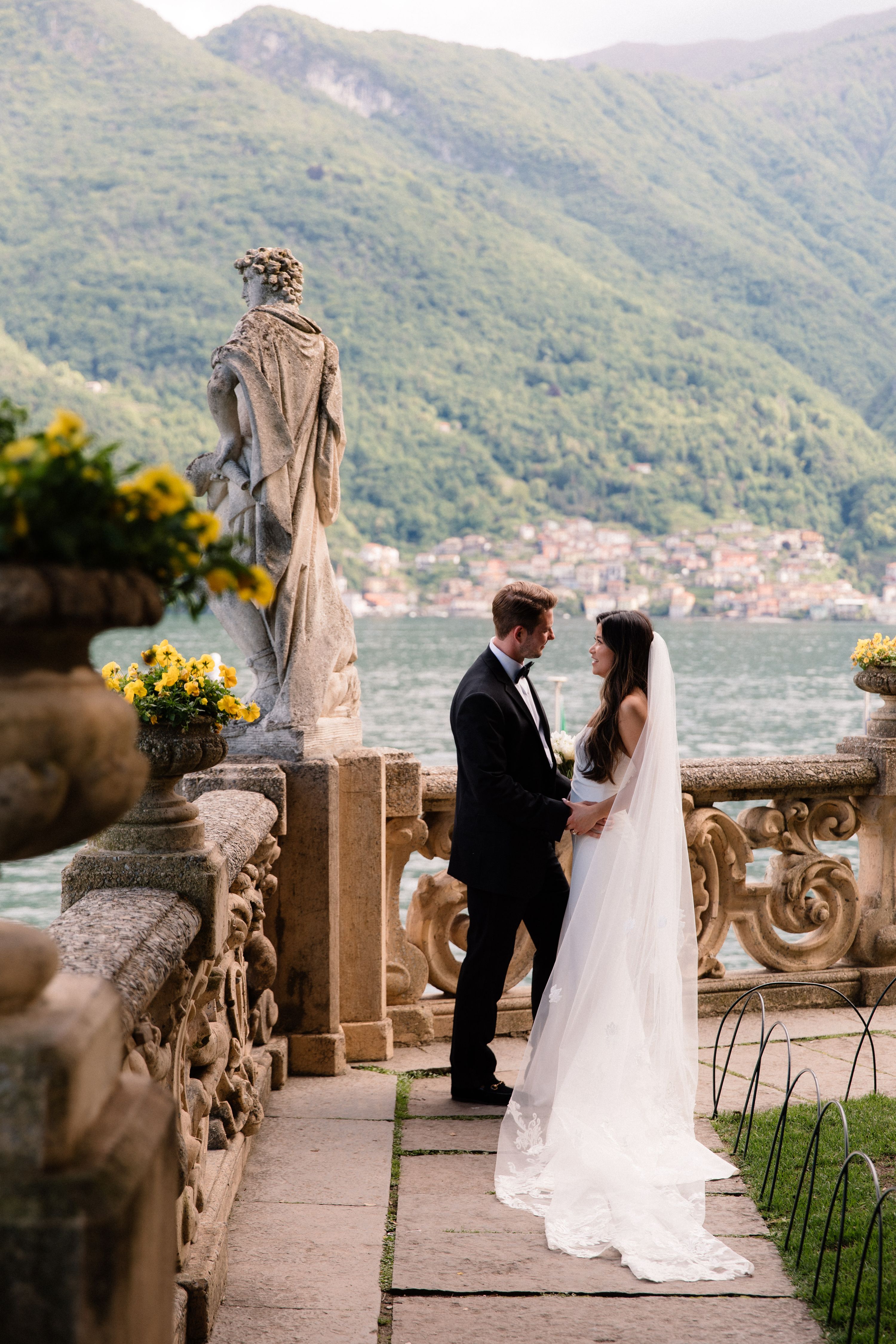 Bride and groom looking at each other with Lake Como and rolling hills in the background during their elopement in Italy