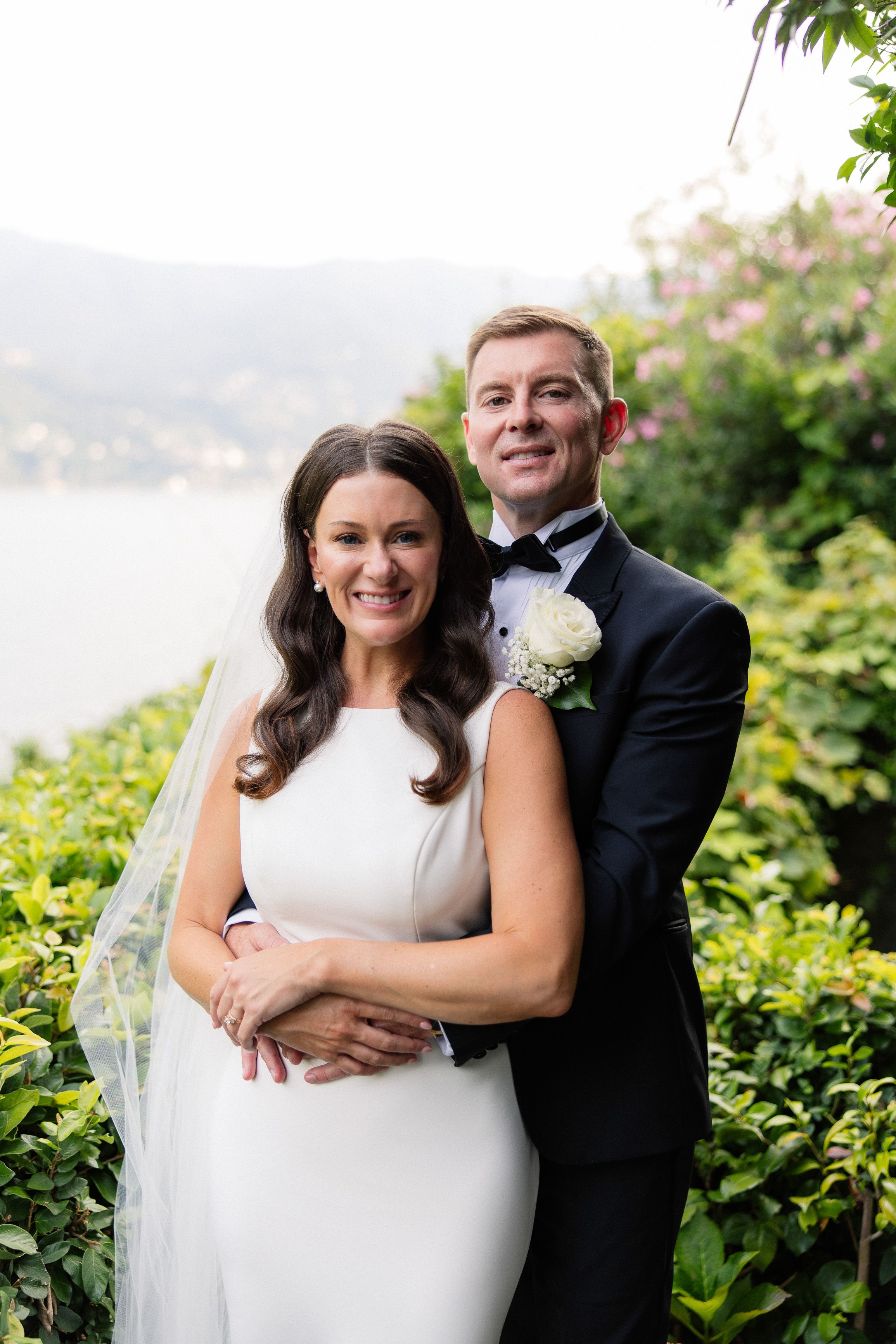 Bride and groom embracing in a garden overlooking Lake Como at a small wedding in Italy