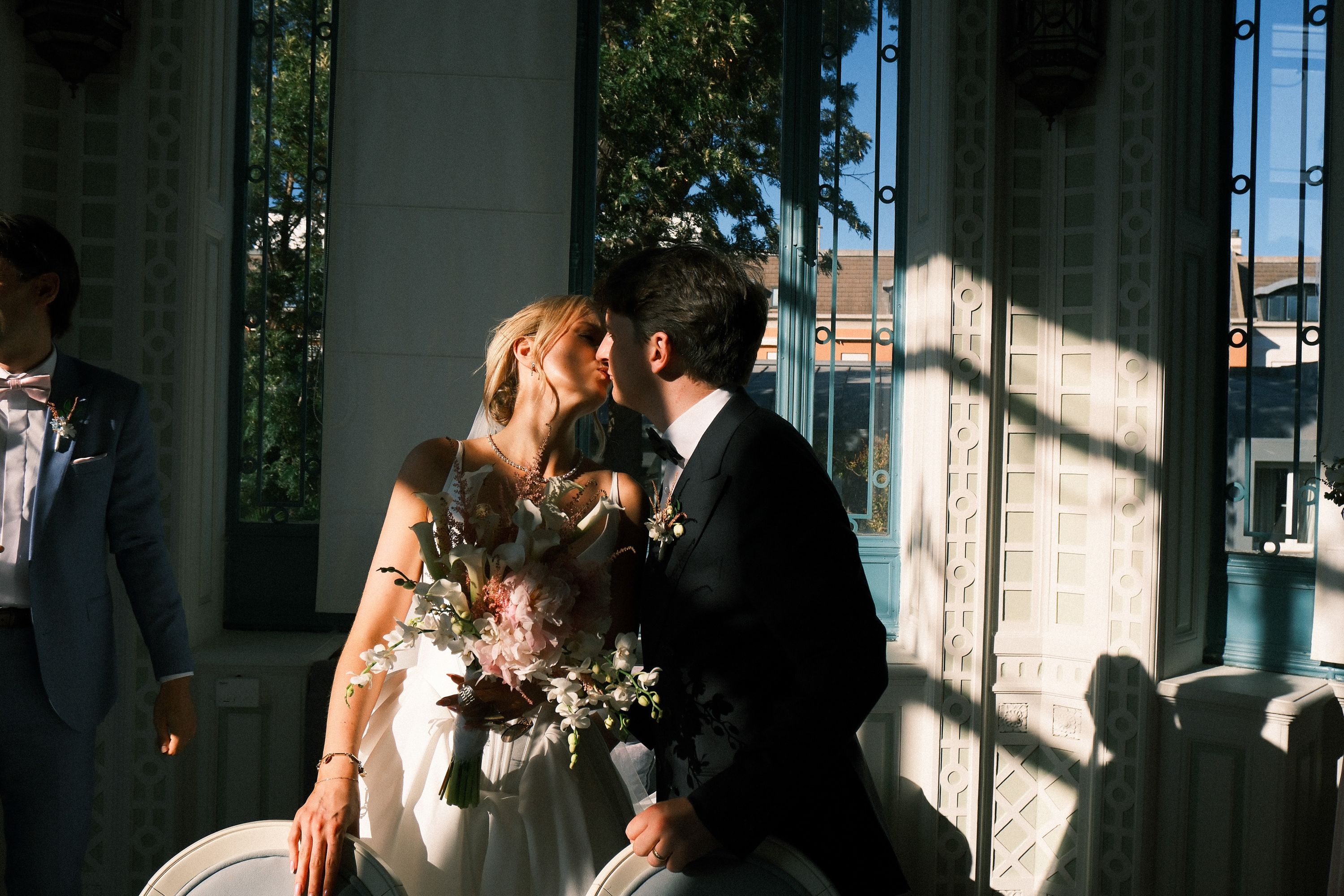 Newlyweds kiss beneath elegant window inside a historic venue during an intimate wedding in Portugal