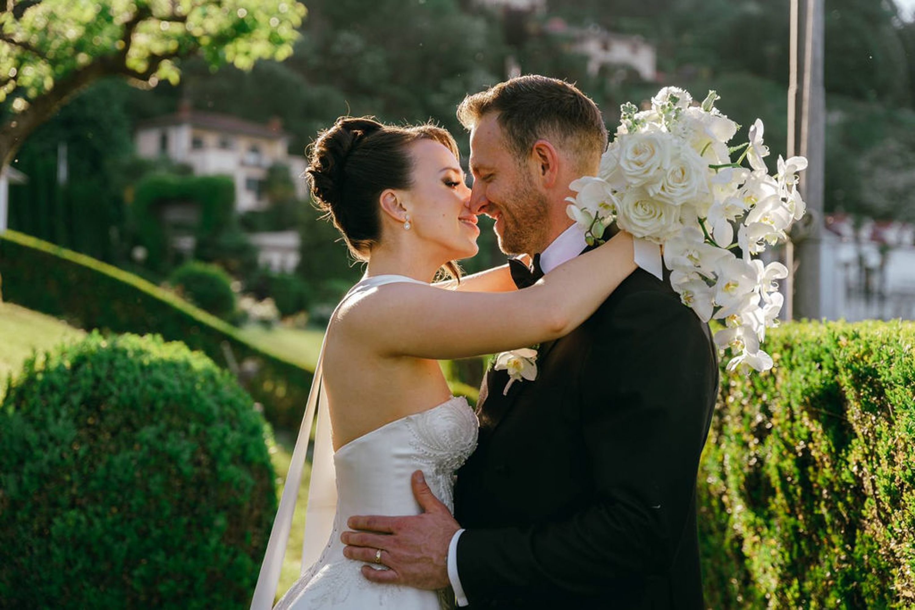 Bride and groom embracing in a manicured garden during an intimate wedding in Italy with elegant white orchids