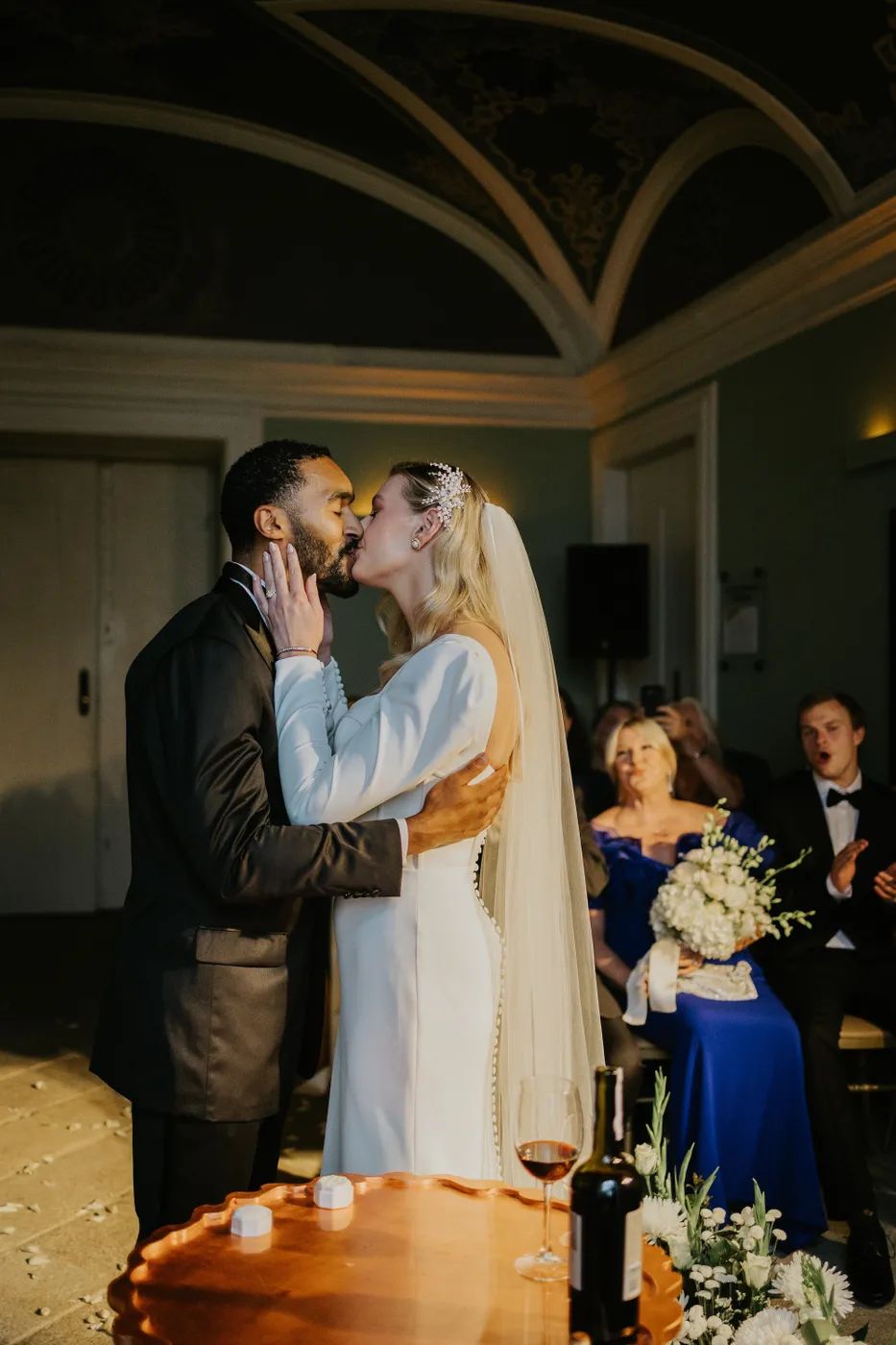 Bride and groom kissing during the ceremony of their destination wedding in Portugal inside a classy-looking event room of a palace