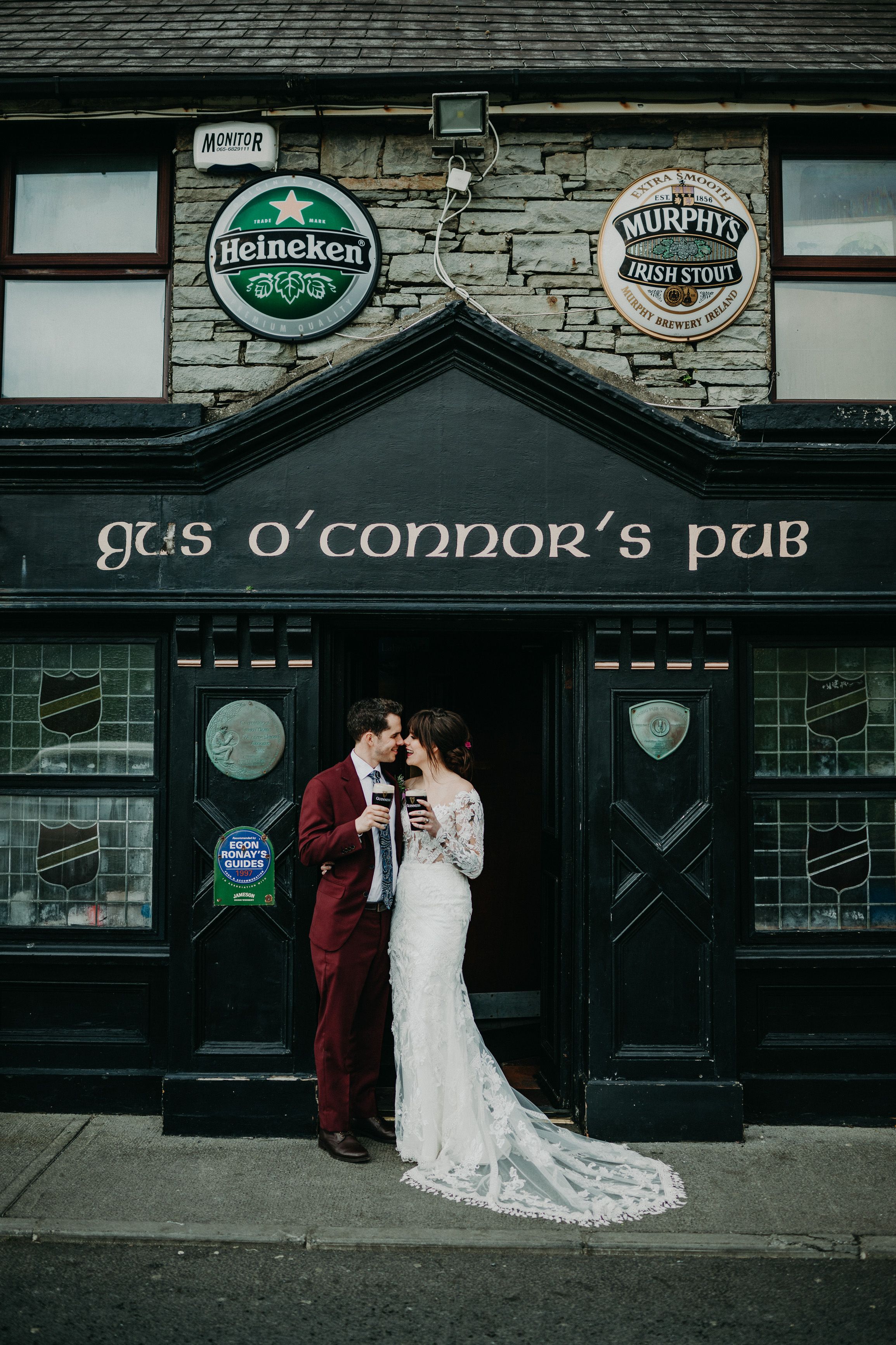 A bride and groom having a drink outside a pub after their intimate wedding in Ireland