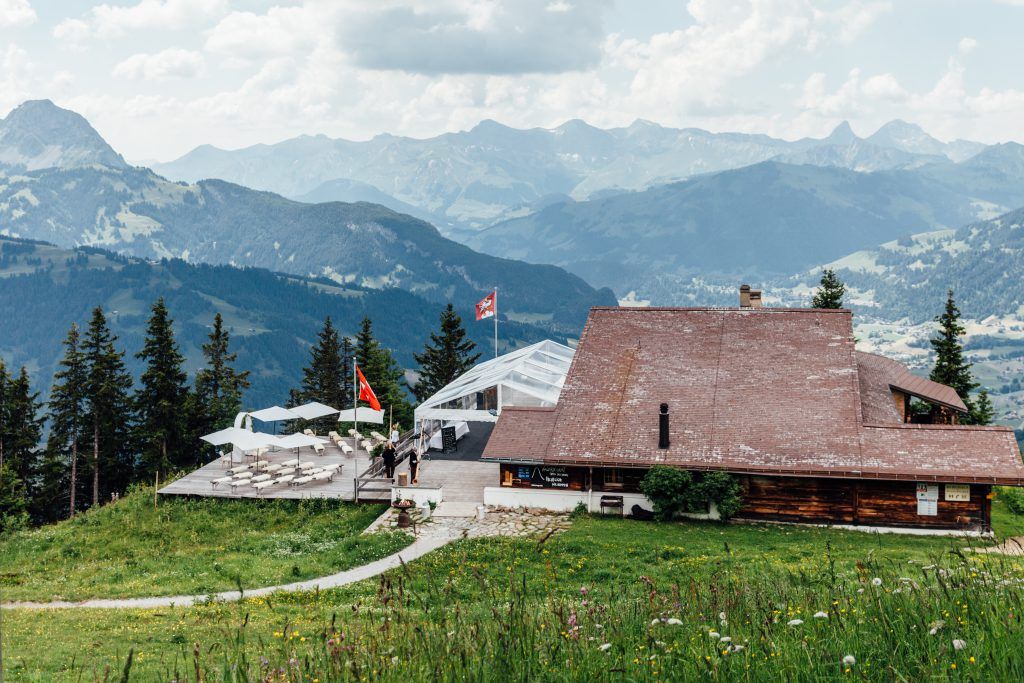 Mountaintop wooden lodge with an outdoor terrace and views of the Alps in the background in Switzerland