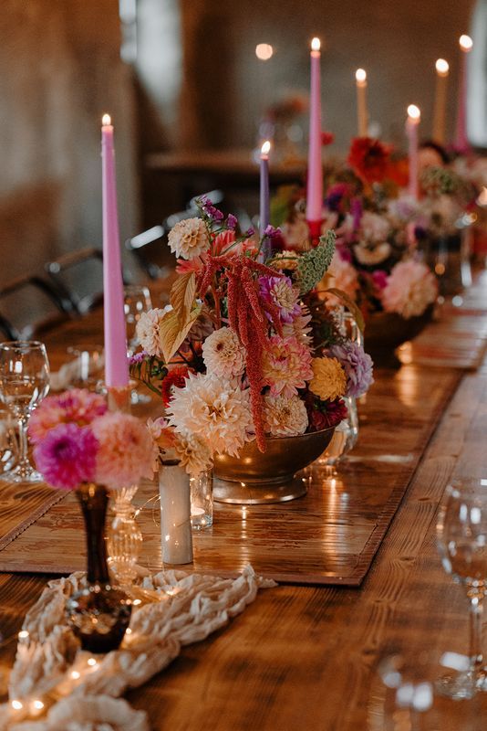 Vibrant spring-themed floral arrangements and lighted pink candles on top of a wooden table
