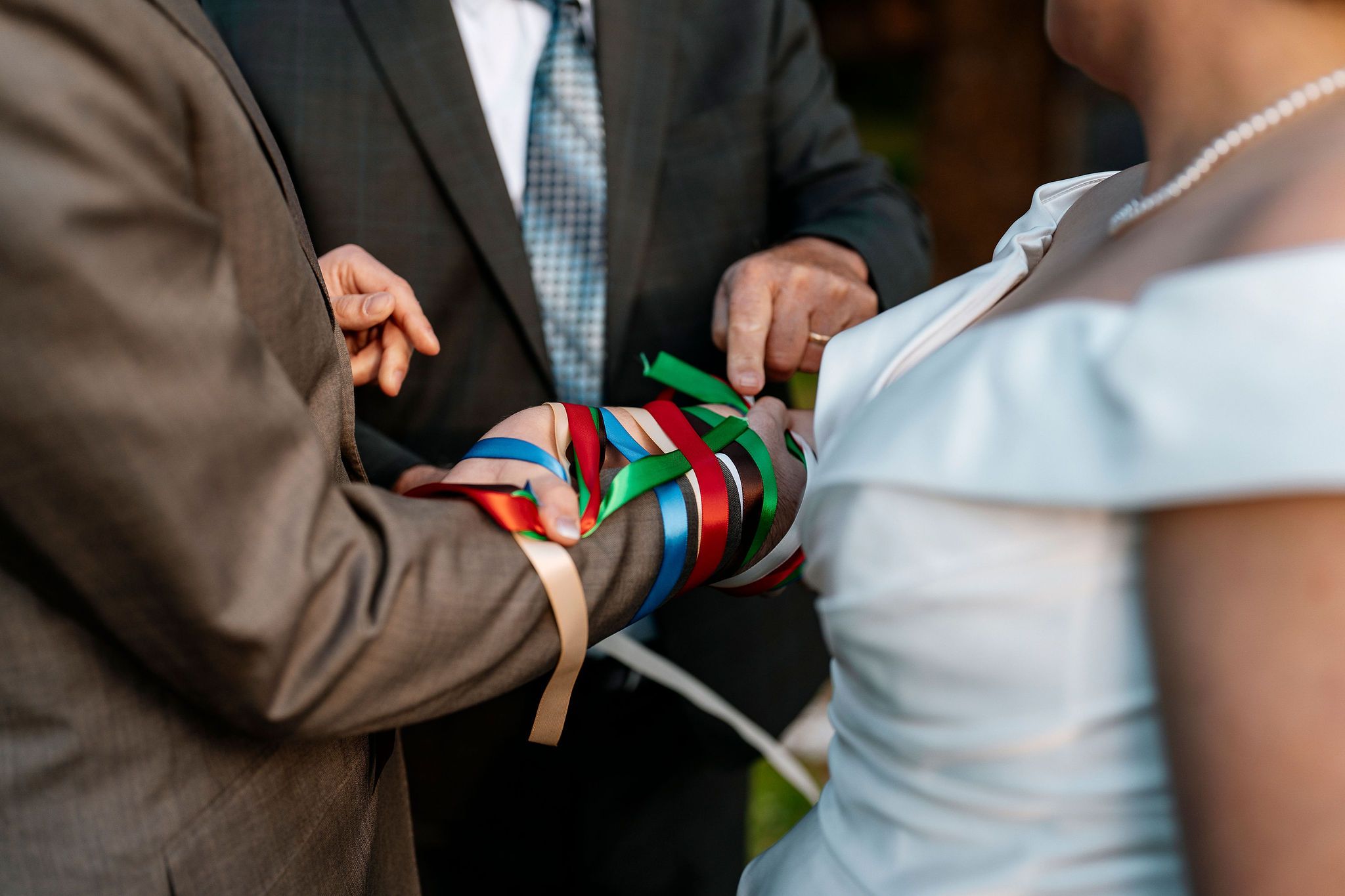 Bride and groom's hands tied in many strings with different colors during a Celtic handfasting ceremony