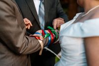 Bride and groom's hands tied in many strings with different colors during a Celtic handfasting ceremony