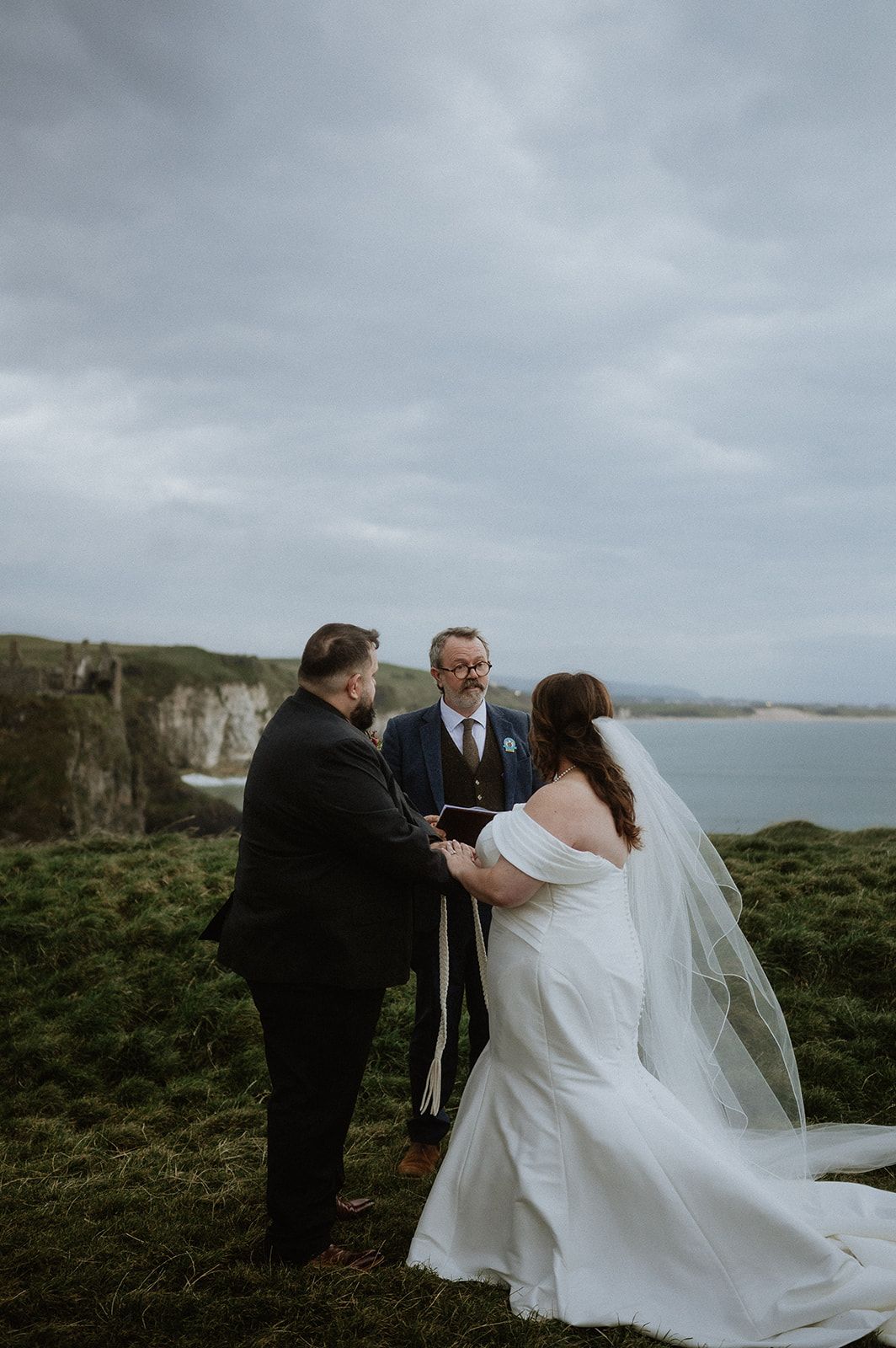 Bride and groom during the ceremony of their elopement in Ireland, doing the hand-fasting tradition